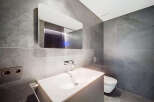 Modern bathroom with sleek gray tile, floating vanity, and frameless mirror.
