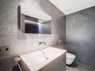 Modern bathroom with sleek gray tile, floating vanity, and frameless mirror.