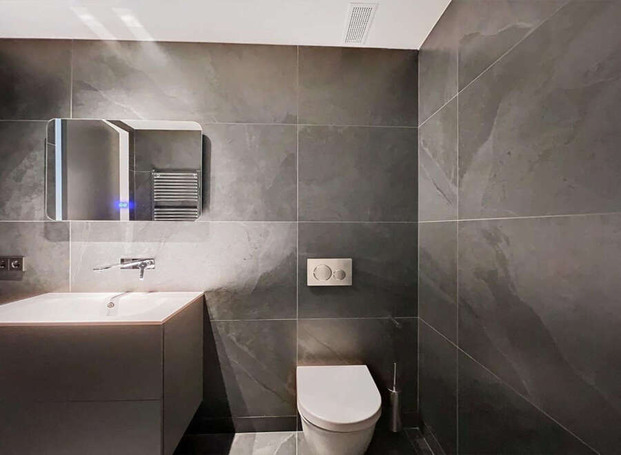 Modern bathroom with dark gray slate tiles, sleek floating vanity, and a contemporary toilet.
