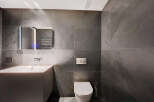Modern bathroom with dark gray slate tiles, sleek floating vanity, and a contemporary toilet.