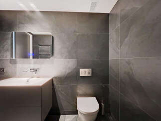 Modern bathroom with dark gray slate tiles, sleek floating vanity, and a contemporary toilet.