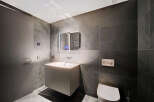 Modern bathroom with dark gray slate tiles, floating vanity, and frameless mirror.