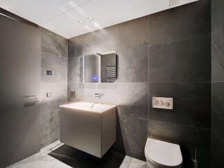 Modern bathroom with dark gray slate tiles, floating vanity, and frameless mirror.