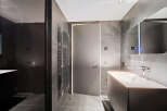 Modern bathroom with dark gray tiles, sleek fixtures, and a frameless glass shower enclosure.