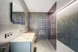 Modern bathroom with sleek gray tile, frameless shower, and contemporary fixtures.