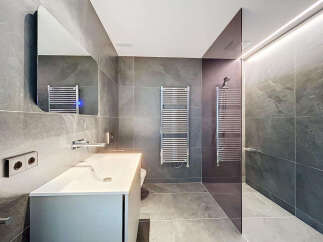 Modern bathroom with sleek gray tile, frameless shower, and contemporary fixtures.