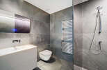 Modern bathroom with sleek gray tile, a floating vanity, and a frameless glass shower enclosure.