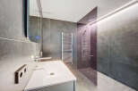 Modern bathroom with sleek gray tile, frameless glass shower, and floating vanity.