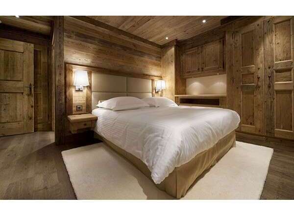 This stunning bedroom showcases rustic elegance with its wooden walls and ceiling, creating a warm and inviting atmosphere.