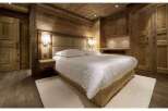 This stunning bedroom showcases rustic elegance with its wooden walls and ceiling, creating a warm and inviting atmosphere.