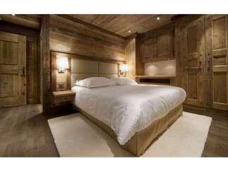This stunning bedroom showcases rustic elegance with its wooden walls and ceiling, creating a warm and inviting atmosphere.