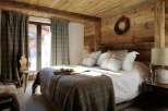 This cozy bedroom features rustic wooden walls and ceiling, creating a warm and inviting atmosphere.