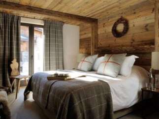This cozy bedroom features rustic wooden walls and ceiling, creating a warm and inviting atmosphere.