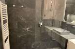 Step into luxury with this stunning bathroom featuring sleek, dark tile and modern fixtures.