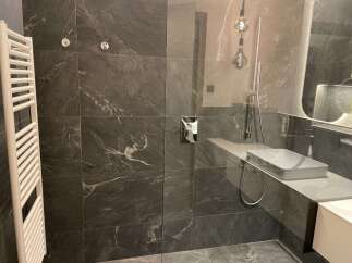 Step into luxury with this stunning bathroom featuring sleek, dark tile and modern fixtures.