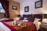 Cozy bedroom with wooden walls and a comfortable double bed, featuring a warm color scheme and stylish decor.