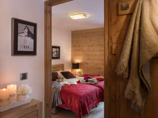 Cozy chalet bedroom with twin beds, wooden walls, and a warm atmosphere.