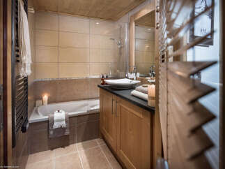 This luxurious bathroom boasts a spacious bathtub, a sleek vanity with ample storage, and a walk-in shower, perfect for relaxation after a day on the slopes.