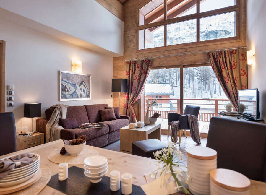 This stunning chalet boasts a spacious open-plan living area with floor-to-ceiling windows offering breathtaking mountain views.