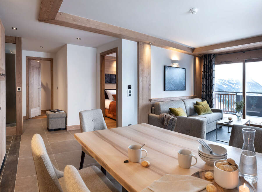 This stunning apartment boasts a spacious open-plan living area with a modern kitchen, dining table, and comfortable seating, perfect for relaxing after a day on the slopes.