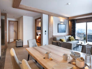 This stunning apartment boasts a spacious open-plan living area with a modern kitchen, dining table, and comfortable seating, perfect for relaxing after a day on the slopes.