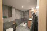 This stunning bathroom boasts modern gray tile, a spacious walk-in shower, and a sleek wooden vanity.