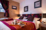 Cozy bedroom with a king-size bed, featuring a rich color palette and patterned headboard.