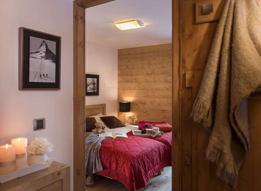 Cozy chalet bedroom with twin beds, wooden walls, and a warm atmosphere.