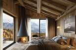 Luxury chalet bedroom with stunning mountain views and a modern fireplace.