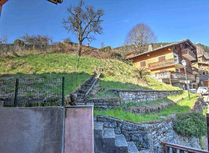 Mountain view property with stone retaining walls and steps leading up to a charming wooden chalet.