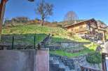 Mountain view property with stone retaining walls and steps leading up to a charming wooden chalet.