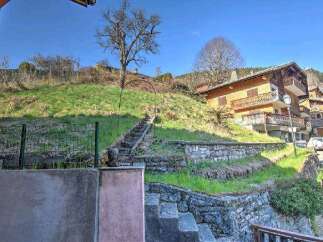 Mountain view property with stone retaining walls and steps leading up to a charming wooden chalet.