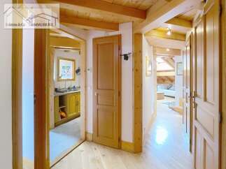 Discover the charm of this inviting property, featuring a warm wooden interior and a well-lit hallway.