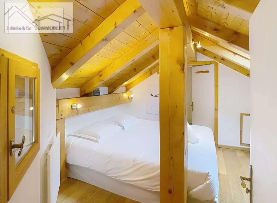 Discover a cozy bedroom with a unique wooden ceiling and beams, creating a warm and inviting atmosphere.