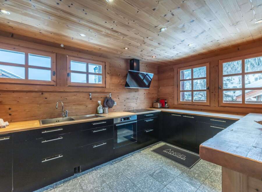 This stunning chalet boasts a modern kitchen with sleek black cabinetry and wood countertops, creating a warm and inviting atmosphere.