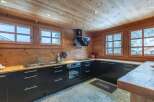 This stunning chalet boasts a modern kitchen with sleek black cabinetry and wood countertops, creating a warm and inviting atmosphere.