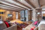 Cozy chalet living room with exposed wooden beams, stone fireplace, and plush sofas.