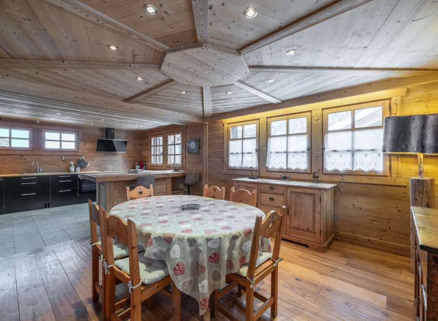 This stunning chalet boasts a spacious open-plan living area with a rustic wooden interior and a cozy dining setting.