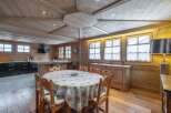 This stunning chalet boasts a spacious open-plan living area with a rustic wooden interior and a cozy dining setting.