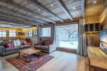 This stunning chalet boasts a spacious living area with exposed wooden beams and a cozy fireplace, creating a warm and inviting atmosphere.