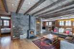 This stunning chalet boasts a cozy living room with a wood-burning stove, exposed wooden beams, and a stone feature wall.