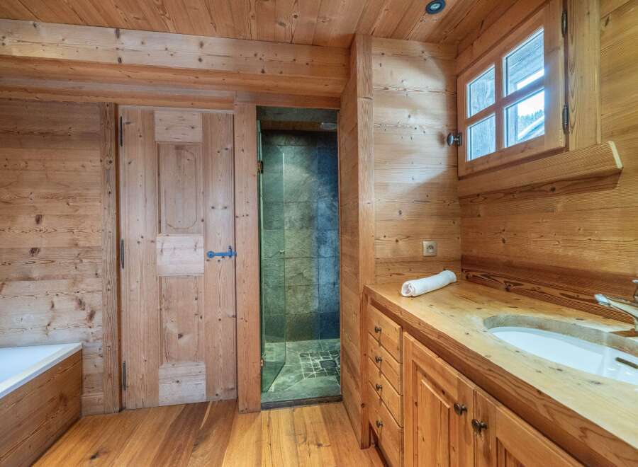 Rustic wooden bathroom with a walk-in shower, wooden vanity with sink, and a bathtub.