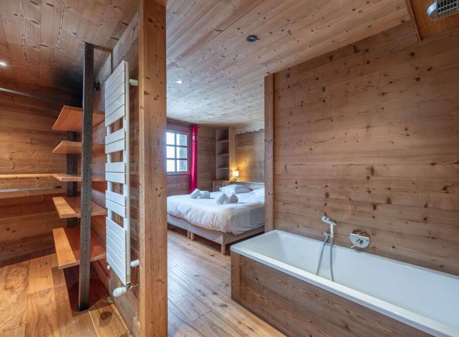 This stunning chalet boasts a luxurious bathroom with a freestanding bathtub and wooden wall paneling, creating a cozy and relaxing atmosphere.