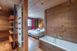 This stunning chalet boasts a luxurious bathroom with a freestanding bathtub and wooden wall paneling, creating a cozy and relaxing atmosphere.