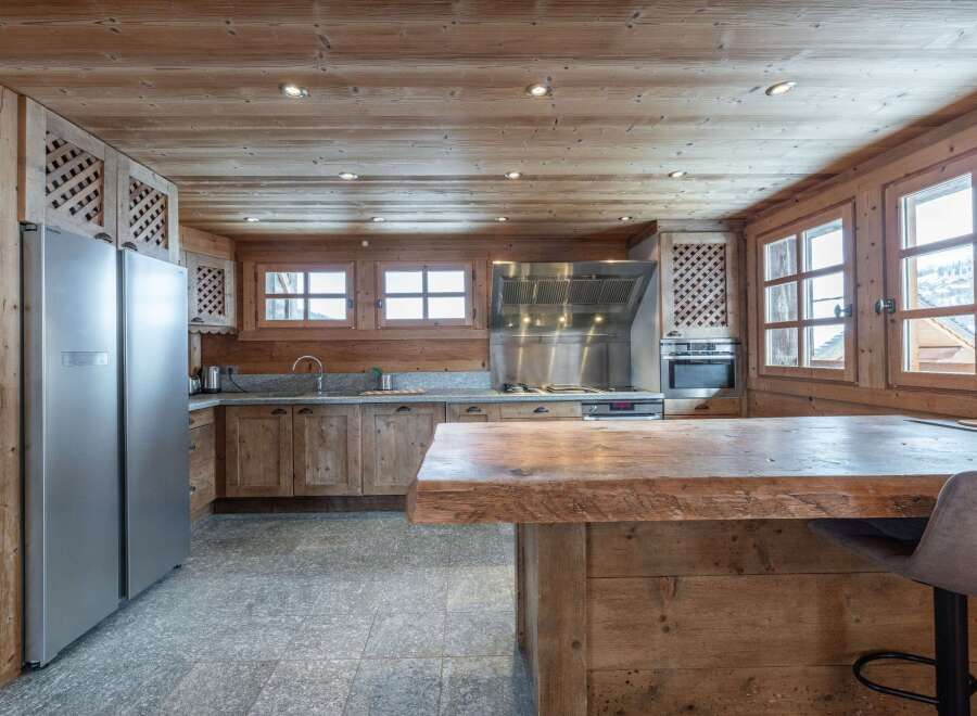 This stunning chalet boasts a rustic-chic kitchen with exposed wooden beams, granite countertops, and top-of-the-line stainless steel appliances.