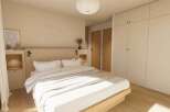 This stunning bedroom boasts a minimalist design with built-in wardrobes and a light oak wood platform bed.