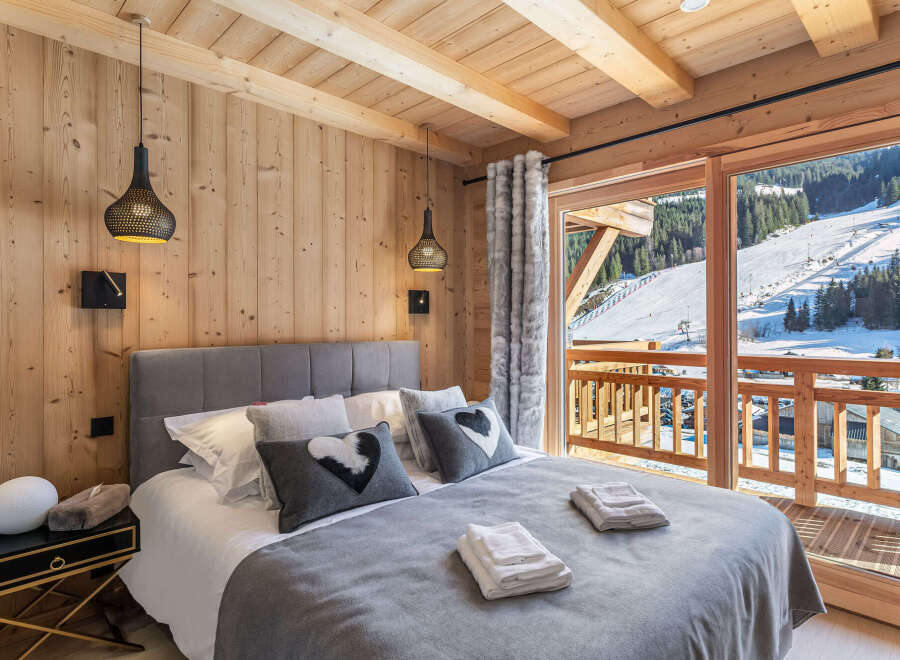 Wake up to breathtaking mountain views from this luxurious chalet bedroom.