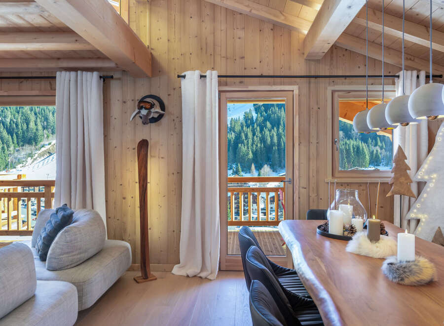 This stunning chalet boasts a spacious open-plan living area with floor-to-ceiling windows offering breathtaking mountain views.