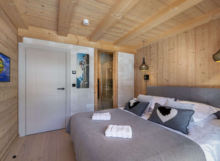 This luxurious chalet bedroom boasts a stunning wood-paneled interior, creating a warm and inviting atmosphere.