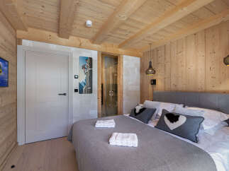 This luxurious chalet bedroom boasts a stunning wood-paneled interior, creating a warm and inviting atmosphere.